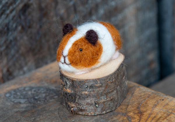 a brown and white stuffed animal sitting on top of a piece of wood